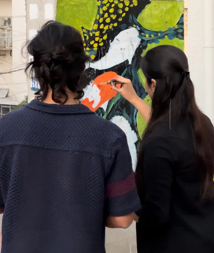 Two people painting a colourful mural together